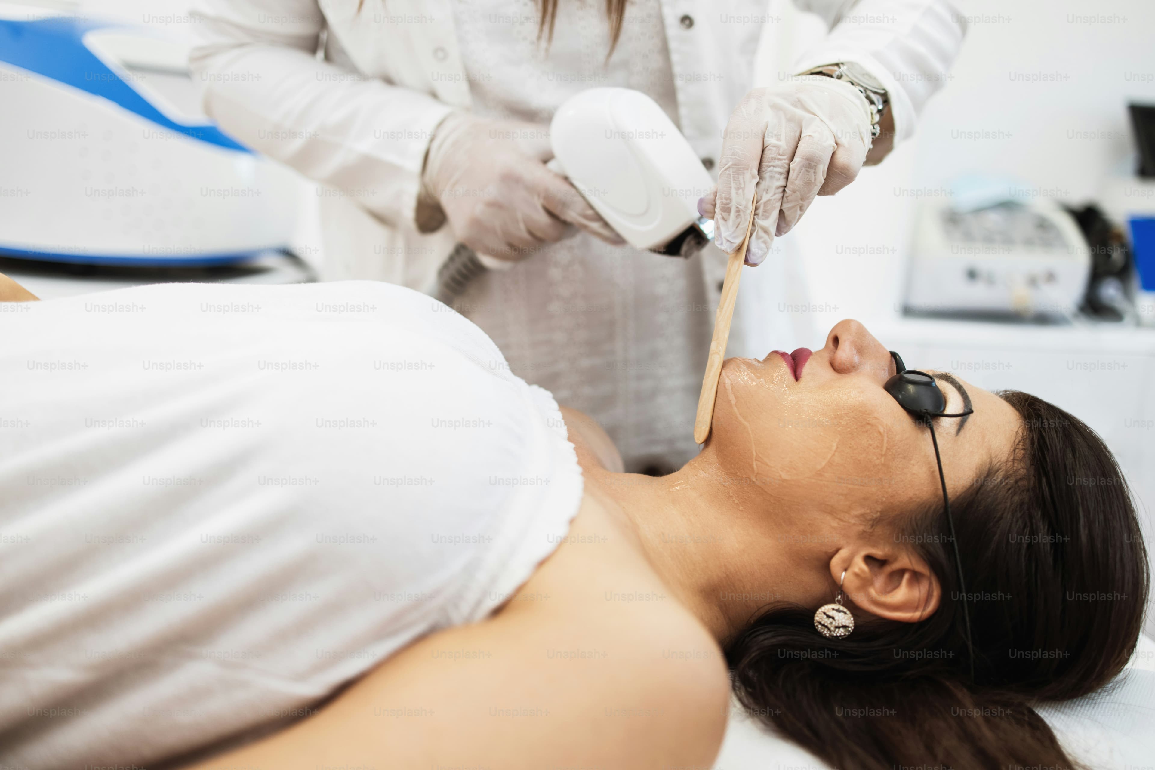 A practitioner preparing a laser hair removal handpiece before treatment
