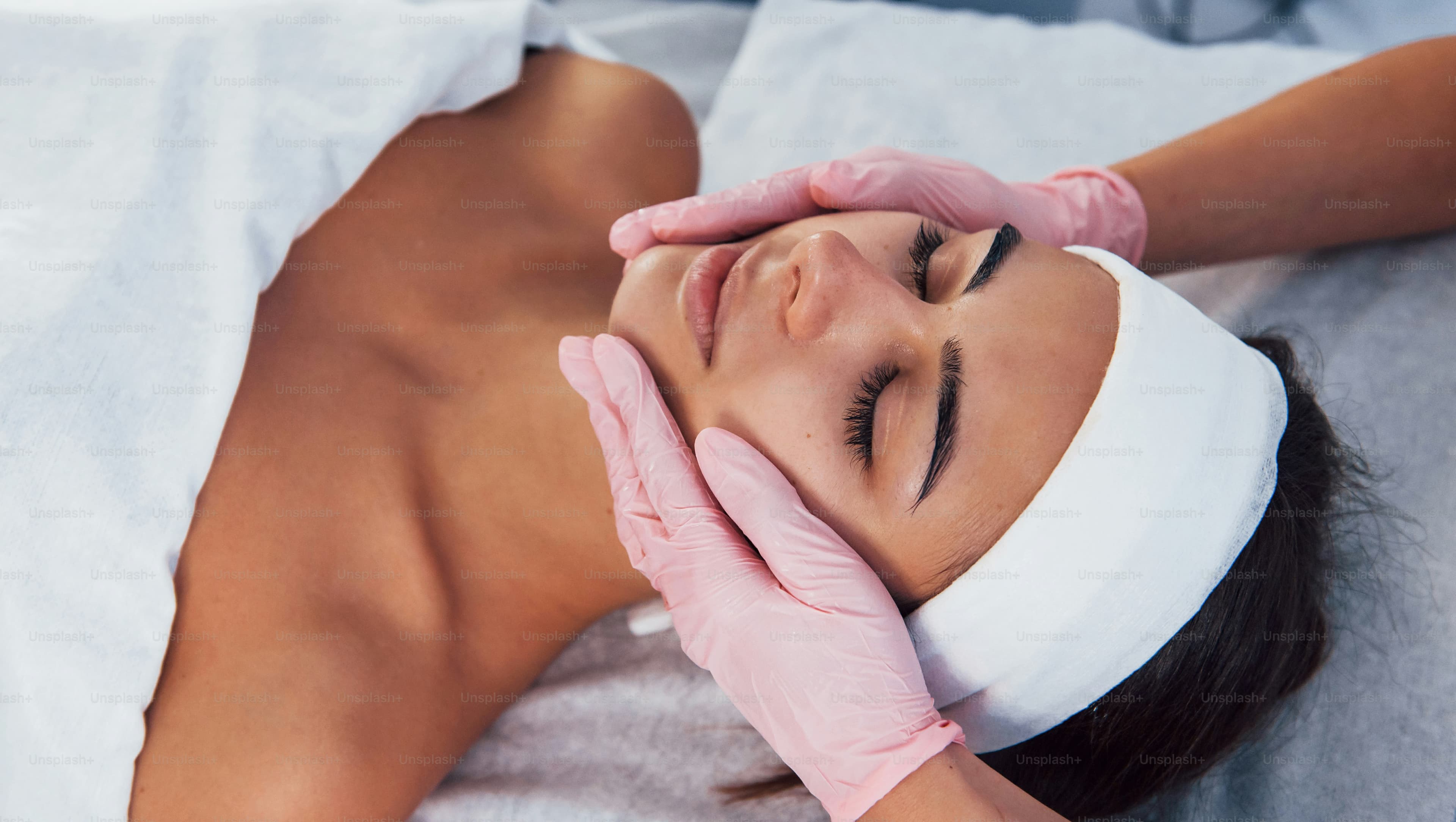 A woman receiving a facial cleansing procedure at a spa salon